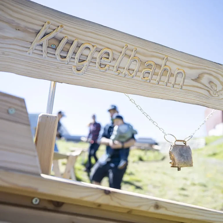 Nahaufnahme eines hölzernen Kugelbahn-Schildes, perfekt für Familienurlaub Samnaun Sommer Spaß im Freien.