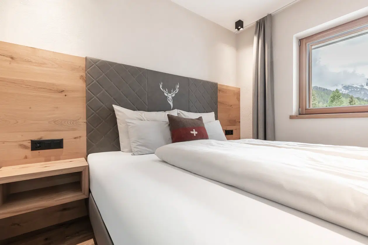 Modernes Schlafzimmer in der Ferienwohnung Samnaun mit Holzakzenten und Bergblick.