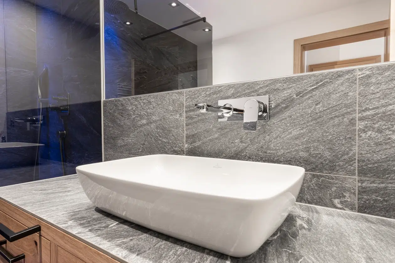 Modernes Badezimmer in der Ferienwohnung Samnaun mit weißem Waschbecken und grauer Marmorarbeitsplatte.