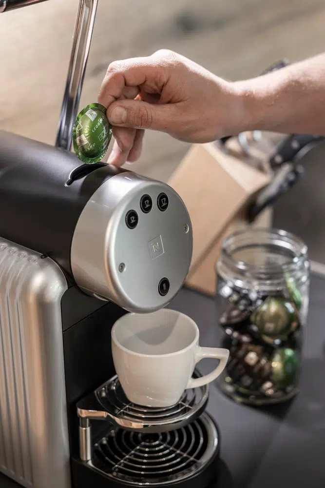 Die Hand legt eine Kaffeekapsel in die Espressomaschine im Ferienhaus Samnaun.