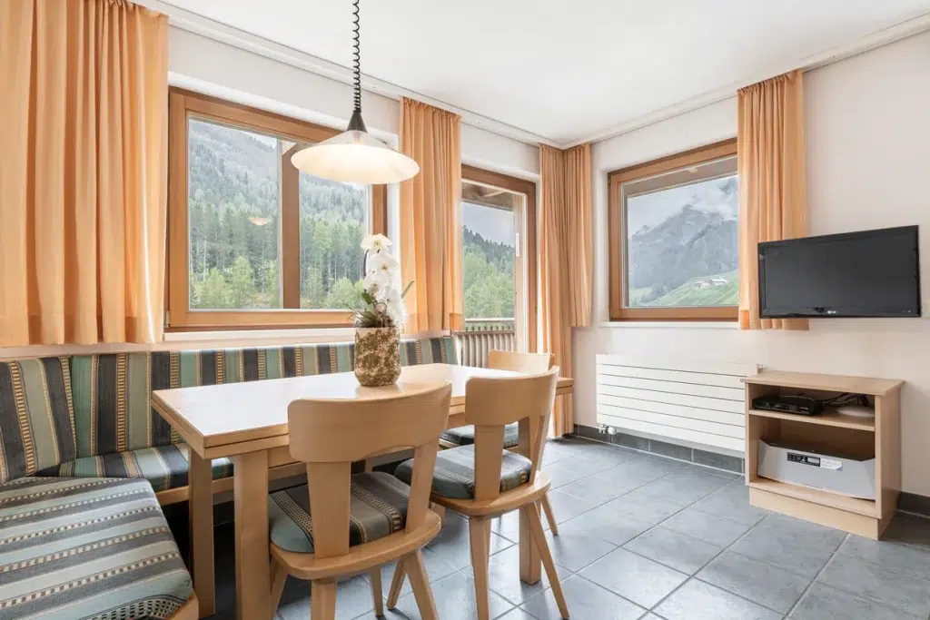 Essecke in den Ferienwohnungen Samnaun mit Holztisch, Sofa und Bergblick.