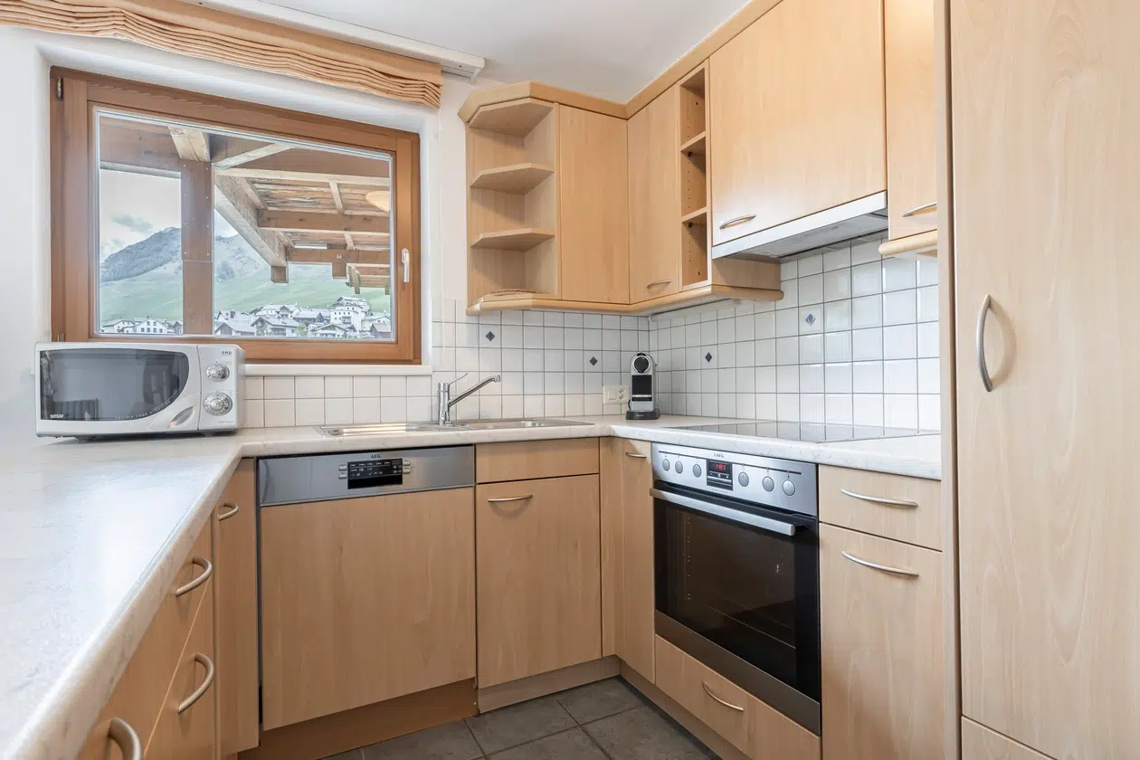Moderne Küche in der Ferienwohnung Samnaun mit hellen Holzschränken und Einbaugeräten.