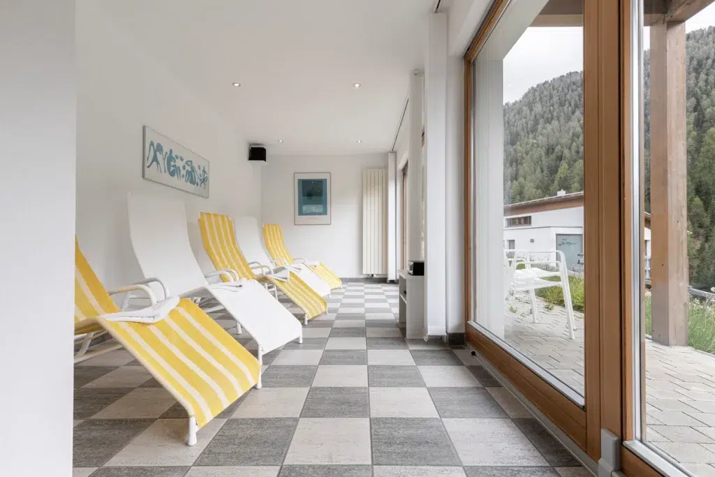 Liegestühle mit gelb gestreiften Handtüchern in der Sonnenterrasse der Ferienwohnungen Samnaun mit Bergblick.