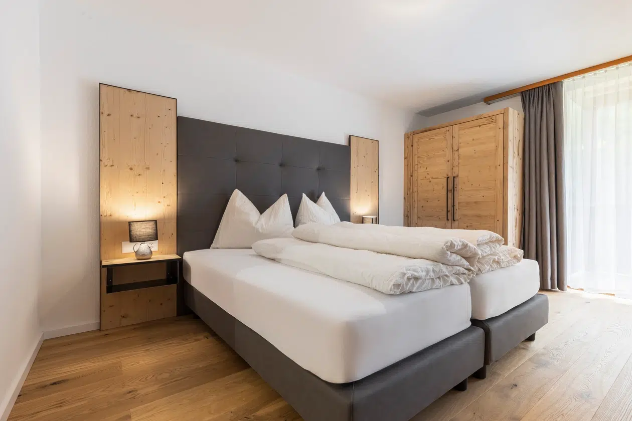Modernes Schlafzimmer mit einem Doppelbett, einem Holzschrank und Nachttischlampen auf jeder Seite.