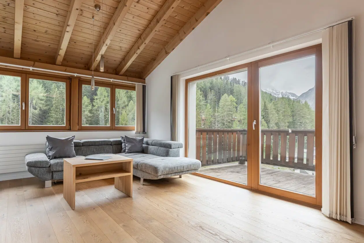 Modernes Wohnzimmer im ferienhaus samnaun mit grauem Sofa, Holzboden und Bergblick.