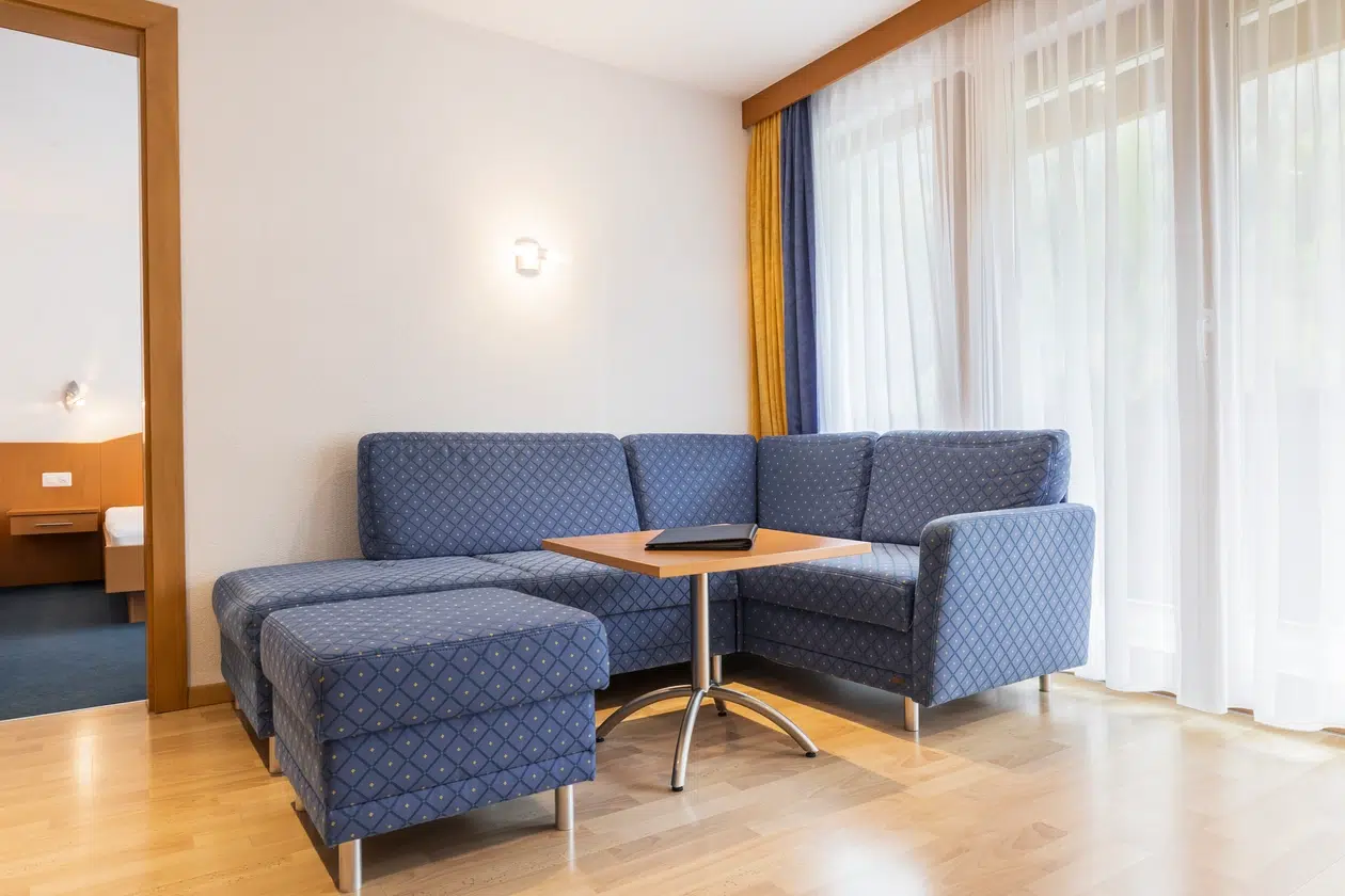 Blau gemustertes Sektionssofa und kleiner Tisch in einer hellen Wohnung in Samnaun mit großen Fenstern.