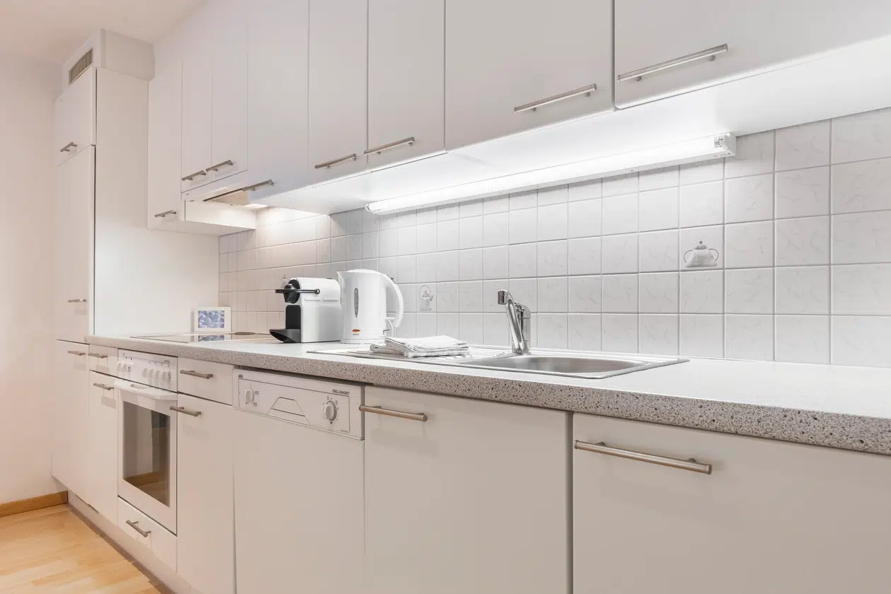 Moderne weiße Küche mit Einbaugeräten im ferienhaus Samnaun, Kaffeemaschine auf dem Tresen.