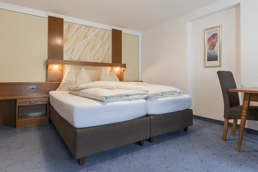 Hotelzimmer im Ferienhaus Samnaun mit Doppelbett, Schreibtisch, Kunstwerken und sanfter Beleuchtung.