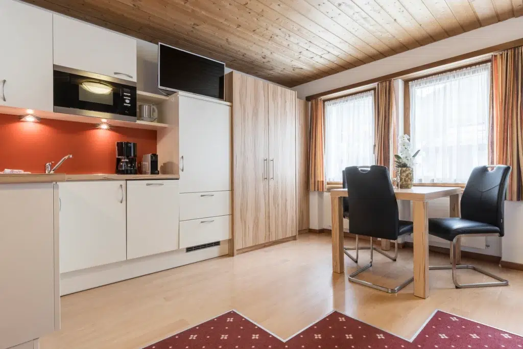 Moderne Küche und Essbereich im Apartment Samnaun mit Holzakzenten und grossen, hellen Fenstern.