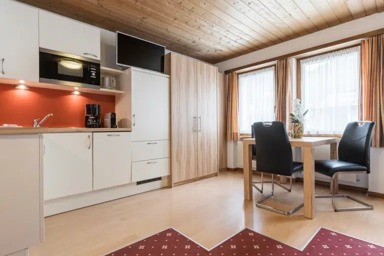 Moderne Küche und Essbereich im Apartment Samnaun mit Holzakzenten und grossen, hellen Fenstern.