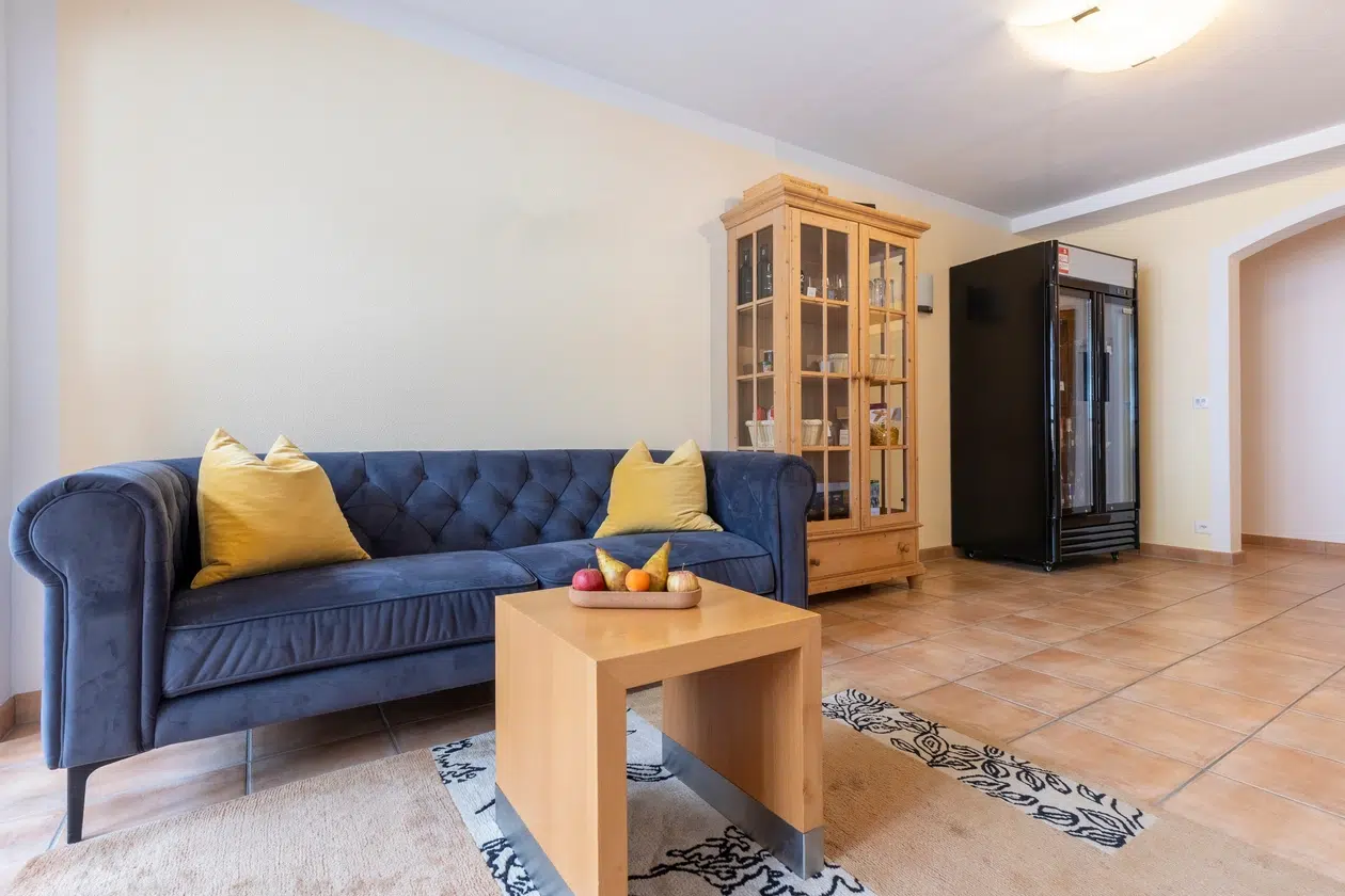 Modernes Wohnzimmer mit blauem Sofa, gelben Kissen, und zusatzleistungen ferienwohnungen Stil.