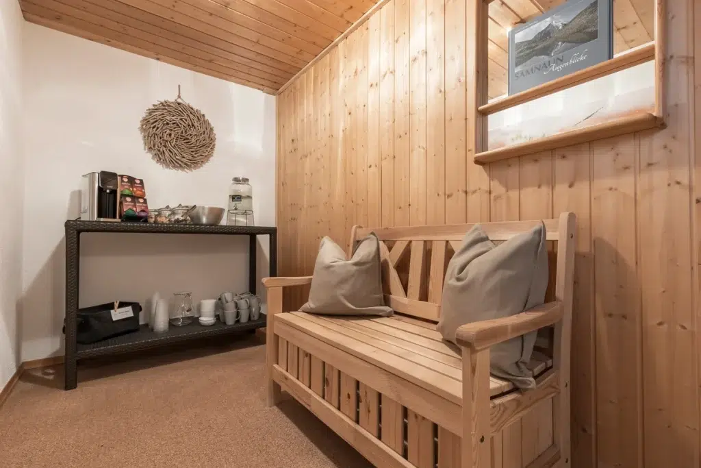 Gemütliche Holzbank mit Kissen neben einer Erfrischungsstation im Ferienhaus Samnaun.