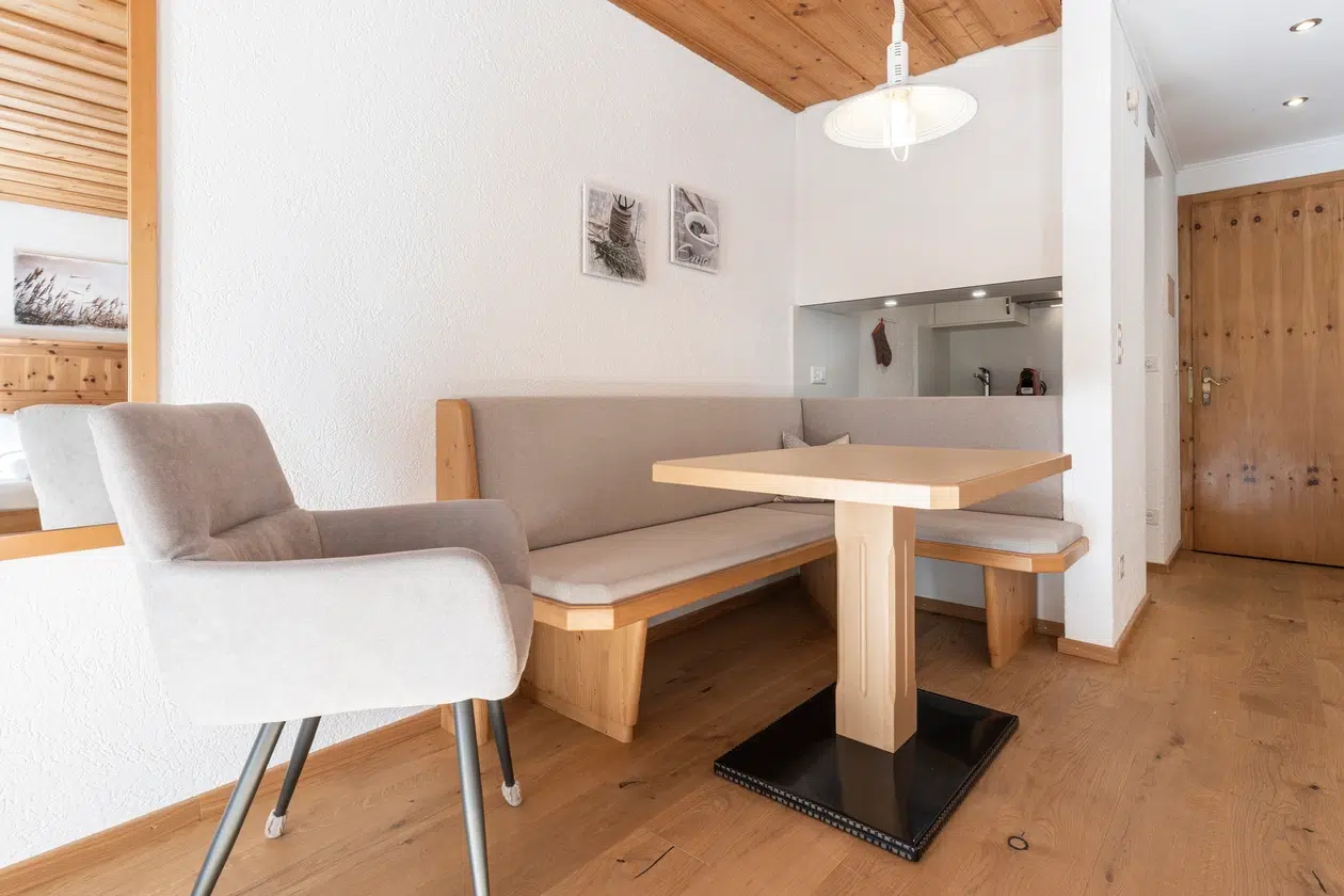 Moderne Essecke im Apartment Samnaun mit Holztisch, Sitzbank und grauem Stuhl.
