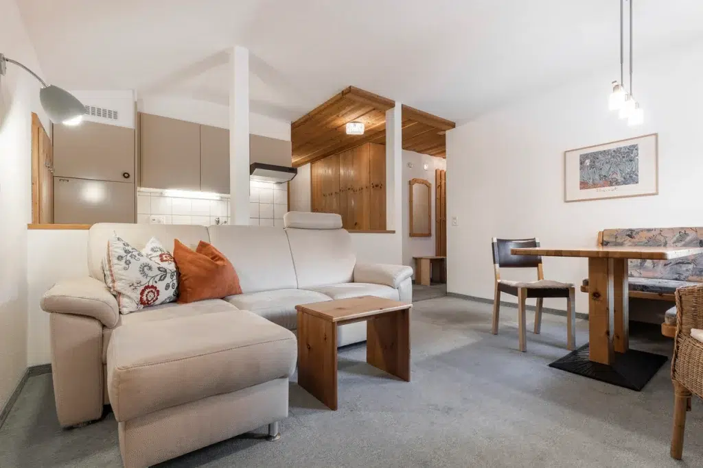 Gemütliches Wohnzimmer mit beigem Sofa, Holzmöbeln und Essecke im Appartement Samnaun.
