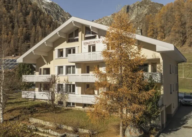 Eine beige unterkunft samnaun Wohnung mit Balkonen, in einer bergigen Herbstlandschaft.