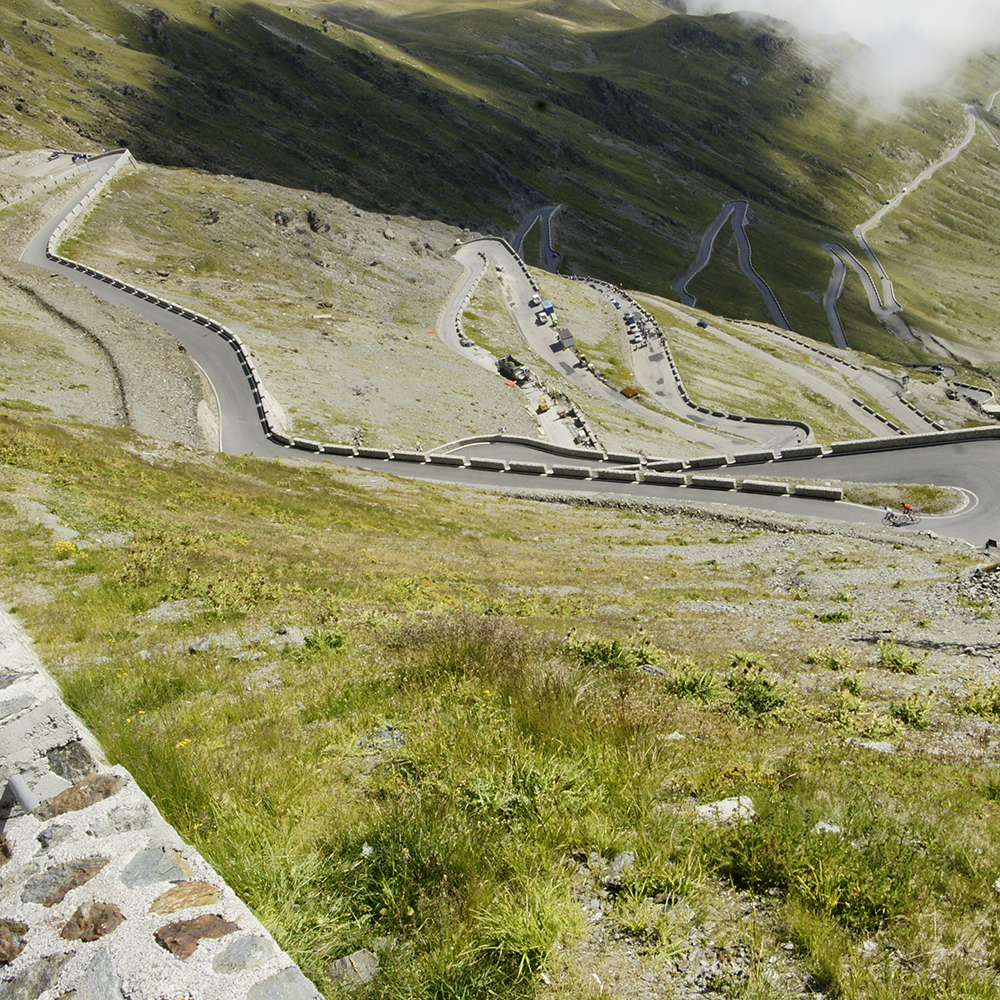 Kurvenreiche Bergstrasse ideal für einen Motorradurlaub Samnaun, mit grasigen und felsigen Pisten.