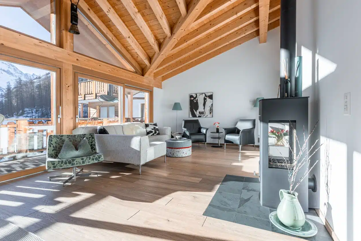 Modernes Wohnzimmer mit Holzbalken, großen Fenstern und Bergblick.