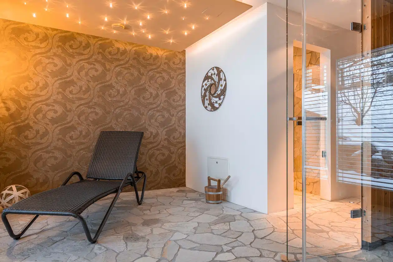 Ein Loungesessel in einem gemütlichen Raum mit Steinfußboden und dekorativen Wänden, in der Nähe einer Glastür.